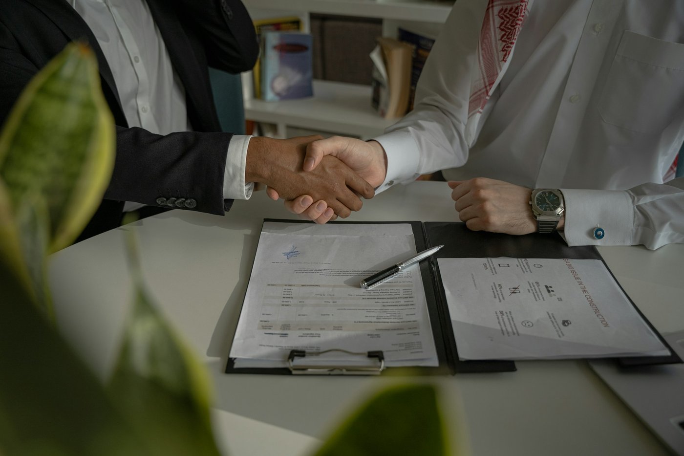 Two people shaking hands over paperwork after agreeing on a business buyout in a divorce