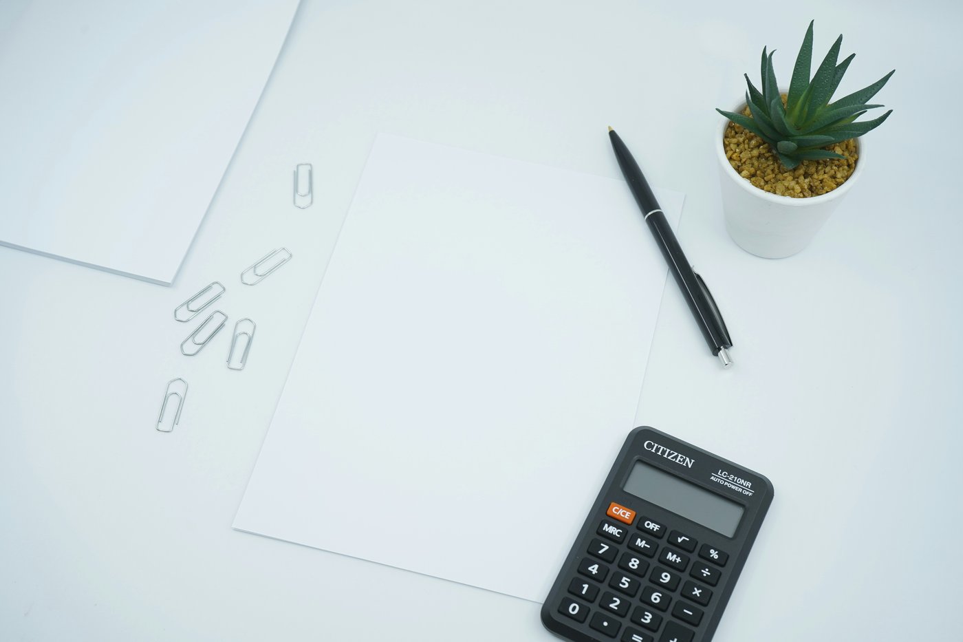Calculator, pen, and blank paper on a white desk, adding up the cost of a divorce in Snohomish County