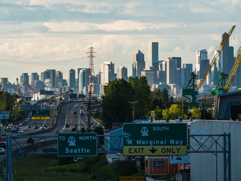 Highway signs pointing north to Seattle with the skyline behind, the drive between King County and Snohomish County courthouses